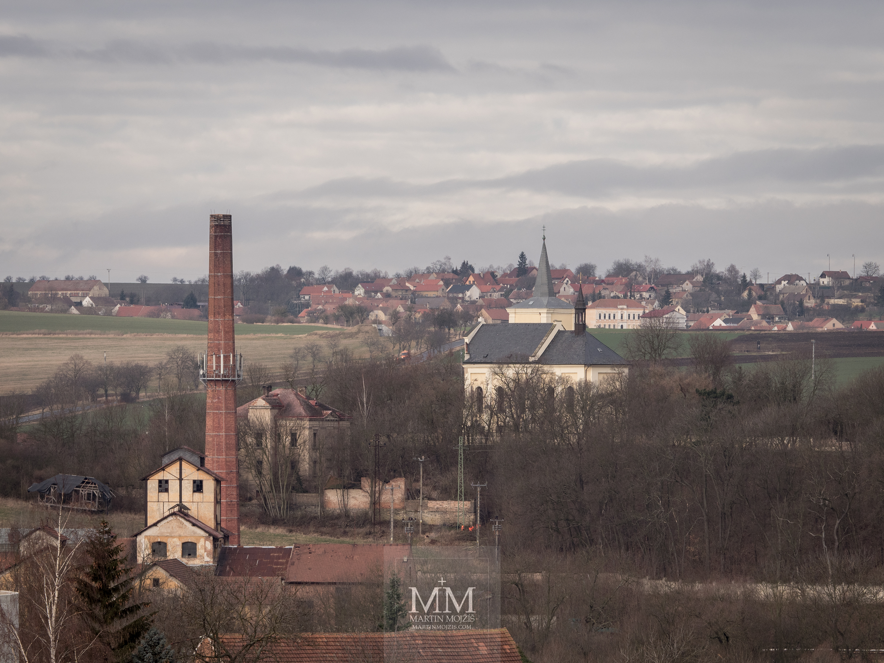 Krajina, v popředí továrna a kostel. Fotografie vytvořená objektivem Olympus M. Zuiko digital ED 40 - 150 mm 1:2.8 PRO.
